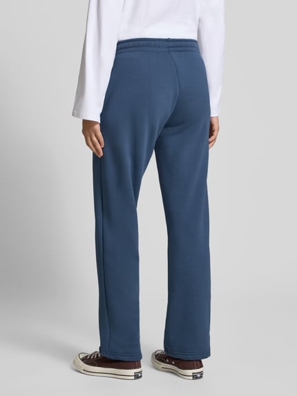 Frauenmodel trägt Sweatpants aus Baumwoll-Mix mit Tunnelzug Modell 'Iconic' von Gina Tricot in Blau, Straight Fit, Ganzkörperansicht Rückansicht.