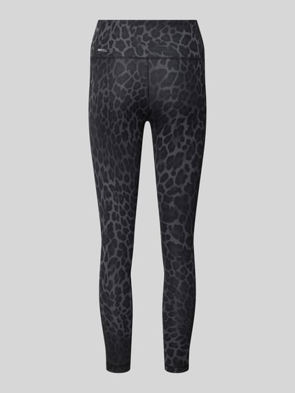 Frauenmodel trägt Skinny Fit Sport-Leggings mit Animal-Print von PUMA, dunkle Farben, Musteroptik, Ganzkörperansicht Rückansicht, Damen Sport-Leggings von PUMA Performance.