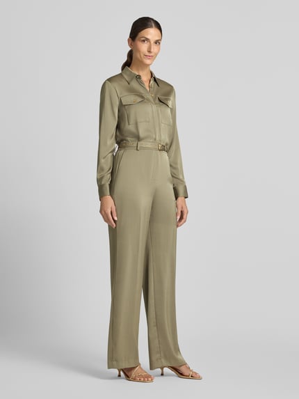 Frauenmodel trägt Jumpsuit mit Taillengürtel von MICHAEL Michael Kors in Khaki, Satin, Crinkle-Optik, lockere Passform, Ganzkörperansicht von vorne.