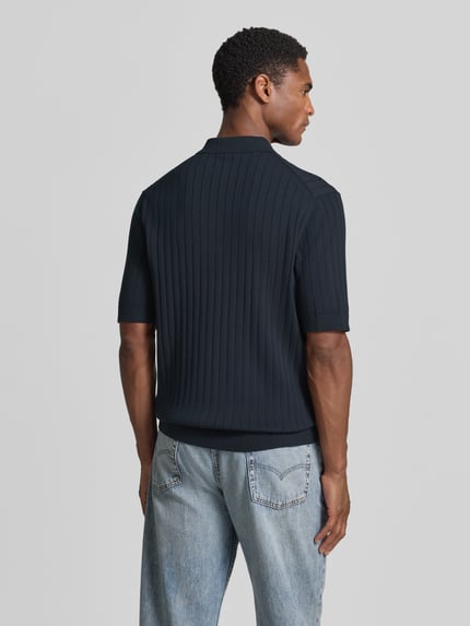 Männermodel trägt Regular Fit Poloshirt mit kurzem Reißverschluss von Drykorn, Reine Baumwolle, dunkel, Modell NIIVAN, Rückenansicht, Ganzkörperansicht Rückansicht.