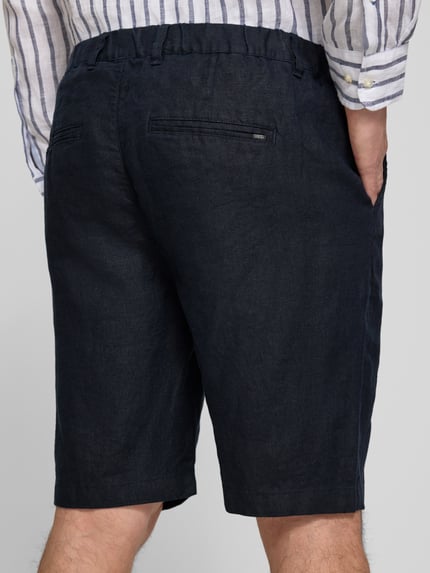 Männermodel trägt dunkelblaue Leinen Shorts mit Eingrifftaschen Modell 'PANDRUP' von Casual Friday, reine Leinenstruktur, Ganzkörperansicht Rückansicht.