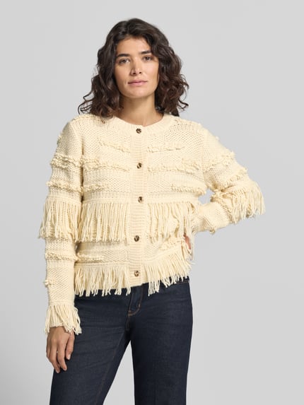 Frauenmodel trägt Strickjacke mit Fransen Modell 'AMELIE' von BRAX in Creme, unifarben, Strickoptik, Ganzkörperansicht von vorne.