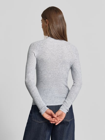 Frauenmodel trägt Strickpullover mit Woll-Anteil von MYON, eng anliegend, Stehkragen, Ripp-Optik, Produktdetails sichtbar, Ganzkörperansicht Rückansicht.