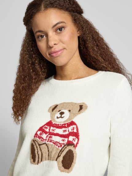 Frauenmodel trägt Rollkragenpullover mit Hundemotiv Weihnachten von ONLY in mehrfarbiger Strickoptik, Nahaufnahme Oberkörper.