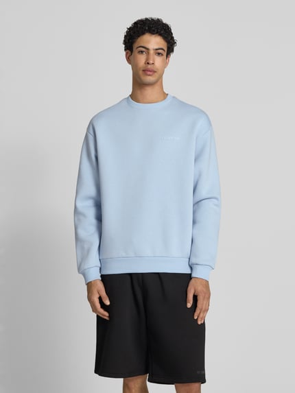 Männermodel trägt Sweatshirt mit Rundhalsausschnitt und Logo von REVIEW aus mieszanka bawełny, krój regular fit, jasnoniebieski, Ganzkörperansicht von vorne