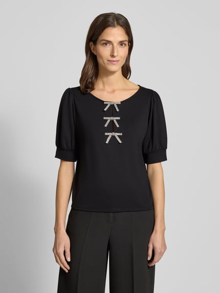 Vrouwenmodel draagt Sweatshirt met Puffärmeln und Schleifen-Applikationen van monari, zwart, viscosemix, regular fit, korte mouwen, ronde hals, vooraanzicht bovenlichaam.