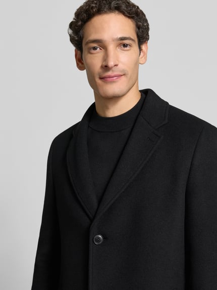 Männermodel trägt Mantel mit herausnehmbarer Steppweste Modell 'C-Hyde BIB' von BOSS, unifarben, Struktur, Reverskragen, Nahaufnahme Oberkörper.