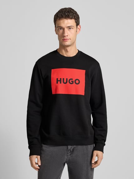 Männermodel trägt Sweatshirt mit Label-Print Modell 'Duragol' van HUGO in zwart met rode print, katoen, losse pasvorm, Ganzkörperansicht von vorne.