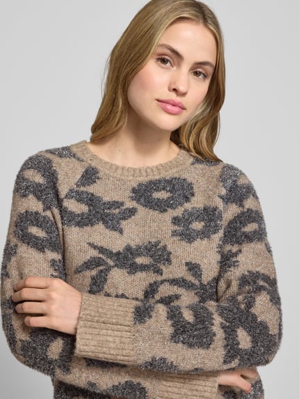 Frauenmodel trägt Strickpullover mit gerippten Abschlüssen Modell 'PANTEA' von FREE/QUENT, braun-graue Blumenmuster, Nahaufnahme Oberkörper. Lockerer Schnitt, Rundhalsausschnitt, Kontext: Rückenlänge 55 cm, Ärmellänge 59 cm bei Größe S.