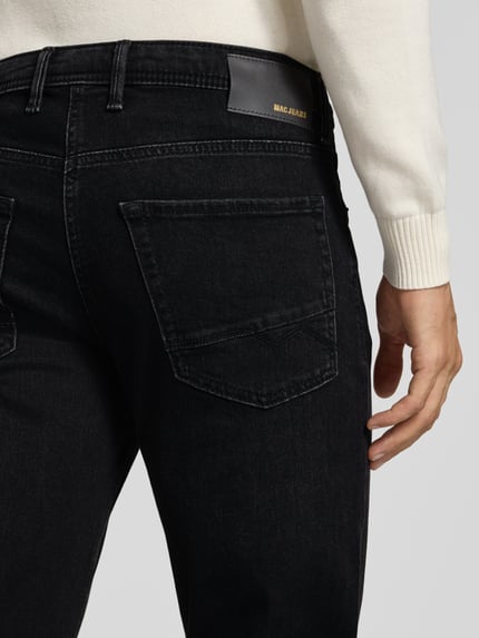 Männermodel trägt Modern Fit Jeans aus Baumwoll-Mix Modell 'Arne' von MAC, 5-Pocket-Design, dark wash, Nahaufnahme Rückansicht.