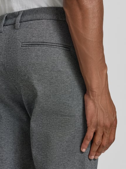 Mężczyznamodel nosi Slim Fit Hose mit Viskose-Anteil in verkürzter Passform od Lindbergh, szara mieszanka wiskozy, kieszeń z tyłu, krój slim fit, skrócony fason, wpuszczane kieszenie, zapięcie na guzik i zamek błyskawiczny, szerokość w rozmiarze M: 42 cm, długość wewnętrzna nogawki w rozmiarze M: 72 cm, zdjęcie: zbliżenie na tył spodni