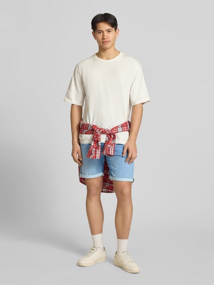Mannenmodel draagt Regular Fit Jeansshorts met omslag model 'RICK' van Jack & Jones, blauwe katoenmix met viscose, used-look, volledige vooraanzicht.