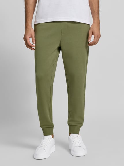 Männermodel trägt olivgrüne Regular Fit Jogginghose aus reiner Baumwolle Modell 'Dayote232' von HUGO, Nahaufnahme Unterkörper, Herren Jogginghose von HUGO.
