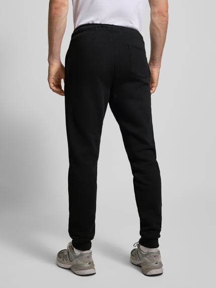 Männermodel trägt schwarze Sweatpants mit Eingrifftaschen Modell 'CERES' von ONLY & SONS aus Baumwollmischung, Gerader-Schnitt, elastischer Bund, elastische Beinabschlüsse, Gesäßtasche, Ganzkörperansicht Rückansicht.