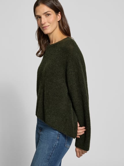 Vrouwenmodel draagt Relaxed Fit gebreide pullover met ronde hals Model 'VITOW' van American Vintage, donkergroen, zachte textuur, dames, ruglengte maat S 56 cm, mouwlengte maat S 57 cm, zijaanzicht, nahaufnahme bovenlichaam.