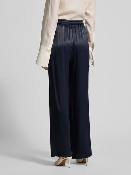 Frauenmodel trägt Wide Leg Hose aus reiner Viskose Modell 'TAVATI' von BOSS in Dunkelblau, Satin-Optik, Ganzkörperansicht Rückansicht