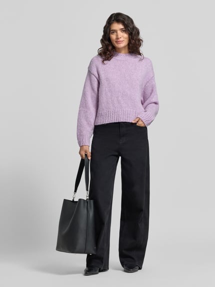 Modelka kobieca ma na sobie sweter z alpaki z prążkowanymi ściągaczami od MARC CAIN, krój regular fit, efekt: jednolity kolor, imitacja dzianiny, krój krótki, ramiona obniżone, okrągły dekolt, długi rękaw z prążkowanym wykończeniem, wykończenie dołu prążkowane, widok całej sylwetki z przodu.
