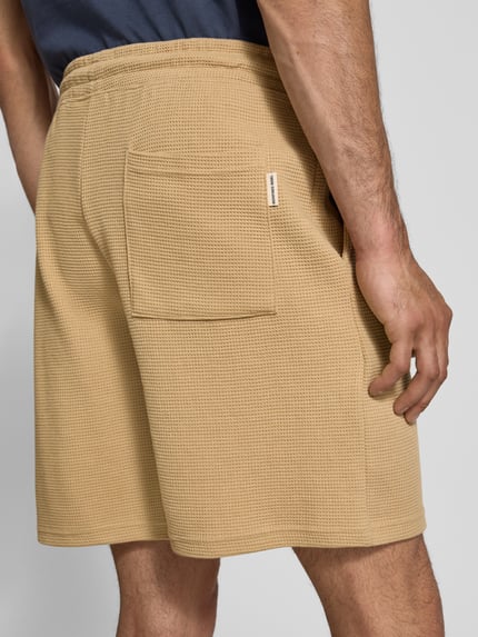 Männermodel trägt Shorts aus Baumwoll-Mix mit Strukturmuster Modell 'KNOX' von Redefined Rebel in Beige, Relaxed Fit, Ganzkörperansicht Rückansicht.