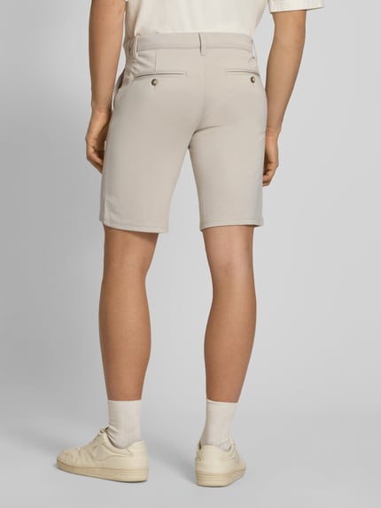 Männermodel trägt Regular Fit Bermudas aus Viskose-Mix Modell 'MARK' von Only & Sons, unifarben, Stretch-Webstruktur, Ganzkörperansicht Rückansicht.