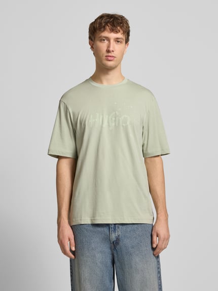 Männermodel trägt Regular Fit T-Shirt aus reiner Baumwolle Modell 'NIEROFIX_U261' von HUGO, Optik: Unifarben, Motiv-Print, Ganzkörperansicht von vorne.