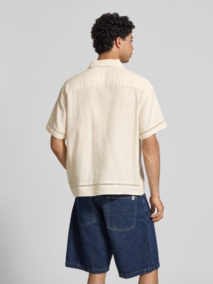 Męski model nosi Relaxed Fit Freizeithemd aus Lyocell-Mix Modell 'Menton' od Jack & Jones, kremowy kolor, bawełna z lyocellem, krótkie rękawy, kent kołnierzyk, z ażurowym florystycznym stebnowaniem, długość pleców w rozmiarze M: 72 cm, szerokość w rozmiarze M: 52 cm, długość rękawa w rozmiarze M: 25 cm, widok całej sylwetki od tyłu.