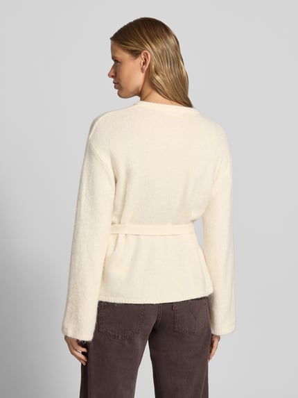 Frauenmodel trägt Cardigan mit Woll-Anteil und Bindegürtel von Gina Tricot, cremefarben, taillierter Schnitt, Rückenansicht, Ganzkörperansicht Rückansicht.
