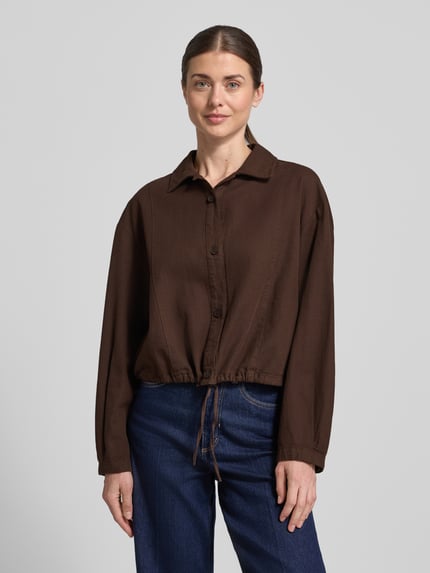 Frauenmodel trägt Relaxed Fit Hemdjacke aus Baumwoll-Leinen-Mix Modell 'Formente' von OPUS, dunkelbraun, Hemdblusenkragen, Knopfleiste, Rückenlänge 44 cm, Ärmellänge 52 cm, Ganzkörperansicht von vorne.