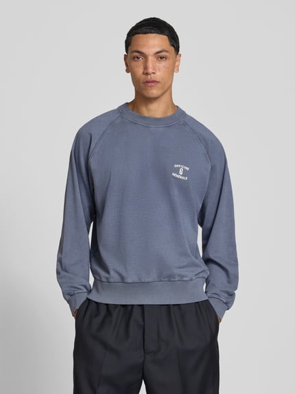 Mannenmodel draagt sweatshirt uit puur katoen van Officine Générale, los model, ronde hals, Raglanmouwen, elastische boordjes, ruglengte maat M: 60 cm, voorkant volledige lichaamsweergave.