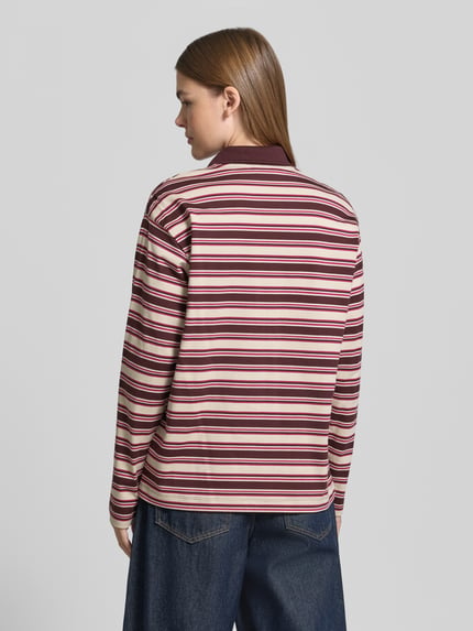 Männermodel trägt Poloshirt mit Logo-Patch von LACOSTE im mehrfarbigen Streifenmuster aus Piqué, Ganzkörperansicht Rückansicht.