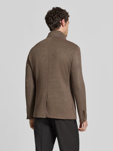 Männermodel trägt Slim Fit Sakko mit Woll-Anteil Modell 'Hypetar' von JOOP! COLLECTION in Braun, glatte und gerippte Texturen, Ganzkörperansicht Rückansicht.
