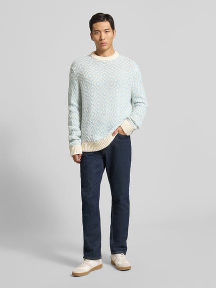 Männermodel trägt Relaxed Fit Strickpullover aus Woll-Mix Modell 'REMI' von SELECTED HOMME mit Allover-Muster, Ganzkörperansicht von vorne.