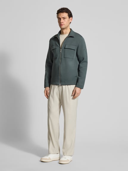 Mężczyzna model nosi Regular Fit Sweatjacke aus Baumwoll-Mix od Marc O'Polo, kolor jednolity, kieszenie na piersi, długi rękaw, bawełna-mix, stehkraag, zamek dwukierunkowy, łatka z logo, faktura scuba, widok całej sylwetki z przodu.