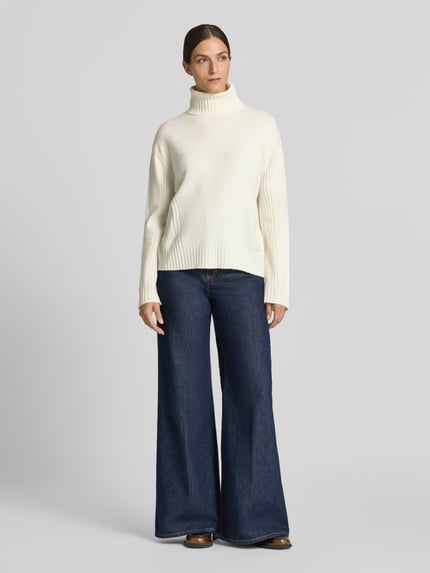 Frauenmodel trägt Relaxed Fit Rollkragenpullover aus reiner Wolle von Liu Jo White in Weiß mit Strasssteinen, gerippten Abschlüssen, Ganzkörperansicht von vorne.
