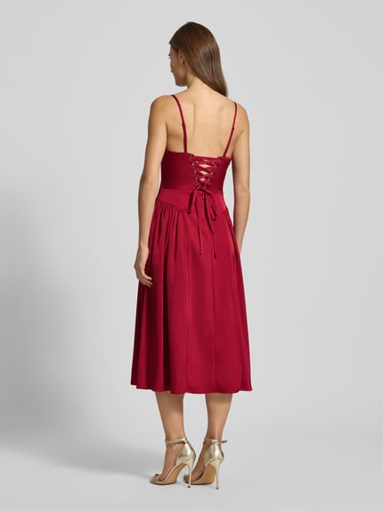 Vrouwenmodel draagt knielanges cocktailkleid met spaghettiträgern van Adrianna Papell in rood, A-lijn, materiaal-mix, stretch, rugaanzicht.