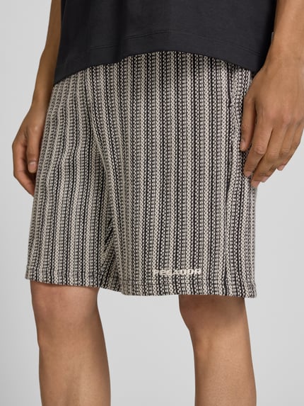 Männermodel trägt Straight Fit Shorts mit Strukturmuster Modell 'Forno' von Pegador aus Reine Baumwolle, Nahaufnahme Oberschenkel.