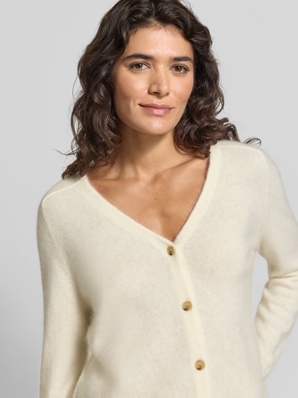 Vrouwenmodel draagt Strickjacke aus Leinen-Kaschmir-Mix mit V-Ausschnitt van MM by Max Mara, regular fit, beige, knoopsluiting, linnen-kasjmiermix, V-hals, lengte rug maat M 51 cm, mouwlengte 59 cm, close-up bovenlichaam.