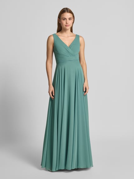 Frauenmodel trägt Maxikleid aus Chiffon in Wickel-Optik von TROYDEN COLLECTION, V-Ausschnitt, A-Linie, fließende Struktur, Ganzkörperansicht von vorne.