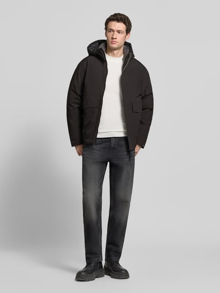 Männermodel trägt Jacke mit Kapuze und Pattentaschen Modell 'LAMOON' von JACK & JONES, Schwarz, Regular Fit, Ganzkörperansicht von vorne. Rückenlänge 72 cm, Schulterbreite 50 cm, Brustweite 60 cm, Ärmellänge 65 cm, verdeckter Reißverschluss, glatte Textur.