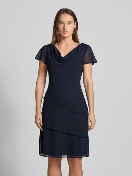 Vrouwenmodel draagt Tailliertes Cocktailkleid mit Volants van Christian Berg Cocktail, donkerblauw, getailleerd, volantmouwen, watervalhals, Ganzkörperansicht von vorne.