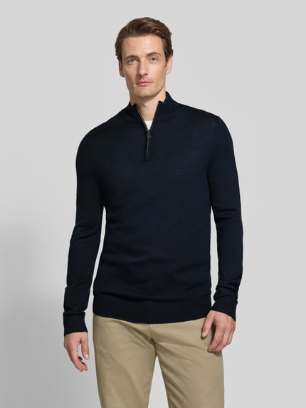 Männermodel trägt Slim Fit Strickpullover aus Woll-Mix mit Troyer-Kragen von Christian Berg Men in Dunkelblau, elastische Abschlüsse, Ganzkörperansicht von vorne.