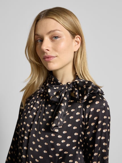 Frauenmodel trägt Cocktailkleid mit Stehkragen von Rinascimento aus reiner Viskose mit tailliertem Schnitt, Schleifen-Detail, Nahaufnahme Oberkörper.