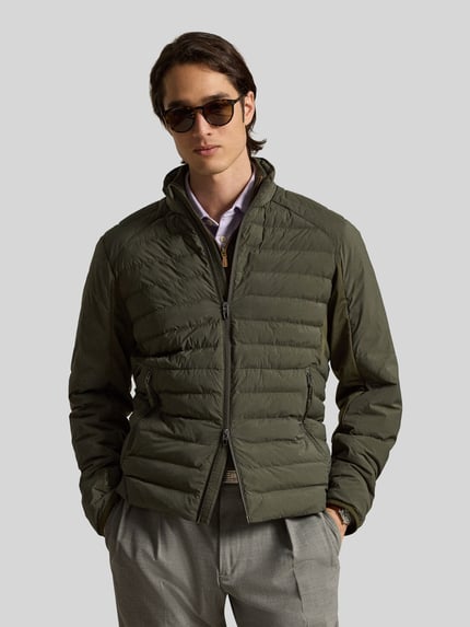 Męski model nosi Regular Fit Sweatjacke mit Steppdetails von Polo Ralph Lauren, oliwkowa z ciemnoszarymi spodniami, tekstura pikowana, Ganzkörperansicht von vorne.