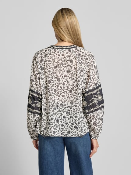 Vrouwenmodel draagt Regular Fit Bluse mit V-Ausschnitt und Stitchings van Milano Italy, witte katoen blouse met zwart allover patroon, ruglengte 60 cm, mouwen 71 cm, allover-look, knoopsluiting, detailstiksels, ganzlichaam achteraanzicht.