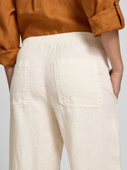 Frauenmodel trägt Leinenhose in verkürzter Passform Modell 'myha linen' von OPUS, cremefarben, strukturierte Oberfläche, Detailaufnahme Rückansicht. Damen Leinenhose, Reines Leinen, Elastischer Bund, Bundweite bei Größe 36: 41 cm, Innenbeinlänge bei Größe 36: 65 cm.