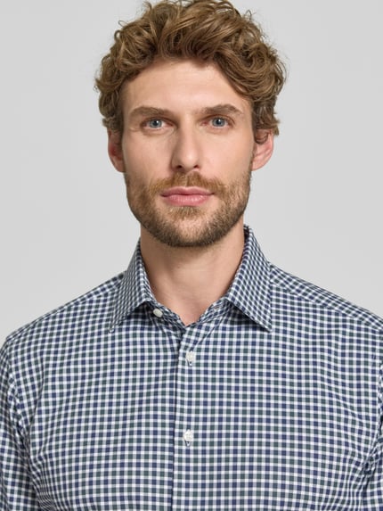 Männermodel trägt Regular Fit Businesshemd aus elastischem Baumwoll-Mix von Christian Berg Men mit Kentkragen, Nahaufnahme Oberkörper.