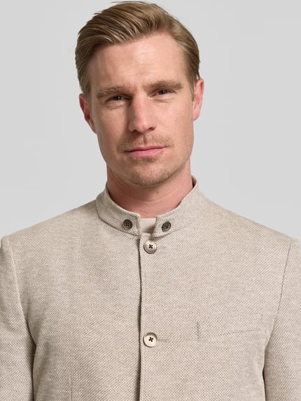 Männermodel trägt Slim Fit Sakko mit Stehkragen von Roy Robson aus Baumwoll-Mix, Knopfleiste, helle Farbe, Nahaufnahme Oberkörper. Rückenlänge bei Größe 50: 76 cm, Schulterbreite: 44 cm, Ärmellänge: 68 cm, Aufgesetzte Taschen.