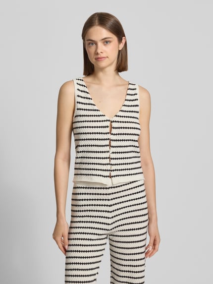 Frauenmodel trägt Strickweste mit V-Ausschnitt und Knopfleiste von REVIEW im Allover-Look aus Material-Mix, Regular-Fit, Ganzkörperansicht von vorne.