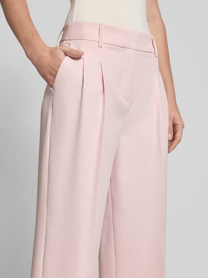 Vrouwenmodel draagt Wide Fit stoffen broek met persplooien van Christian Berg Woman Selection in lichtroze, elastische materiaalmix, steekzakken, haakjes- en ritssluiting, detailopname.
