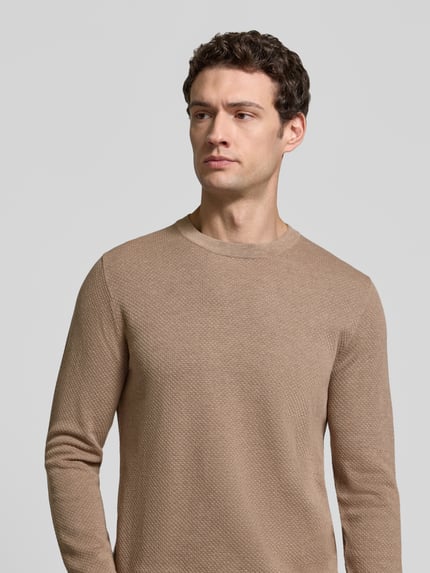 Männermodel trägt Slim Fit Strickpullover aus reiner Baumwolle Modell 'DIAMOND' von DRYKORN in Beige mit feiner Struktur, Nahaufnahme Oberkörper, Rückenlänge 67 cm, Ärmellänge 66 cm.