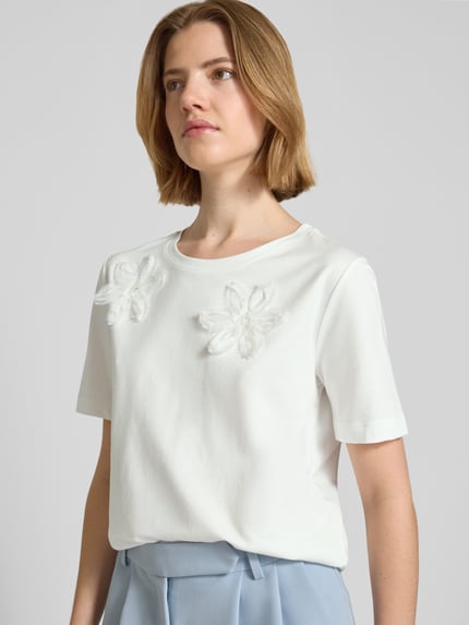 Vrouwenmodel draagt Regular Fit T-shirt met floralem siergarnering van monari, mix van katoen en modal, ronde hals, ruglengte maat 36: 59 cm, nahaufnahme bovenlichaam.
